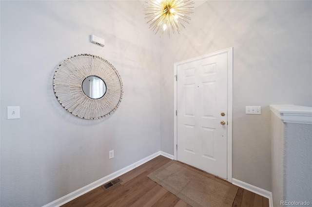 foyer entrance with dark hardwood / wood-style floors and a chandelier