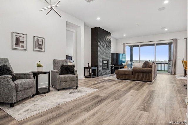 living room with a notable chandelier, light hardwood / wood-style flooring, and a fireplace