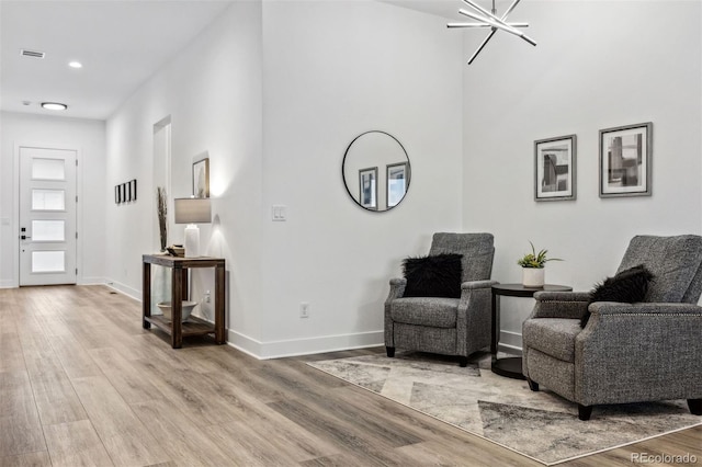 sitting room with light hardwood / wood-style floors and an inviting chandelier