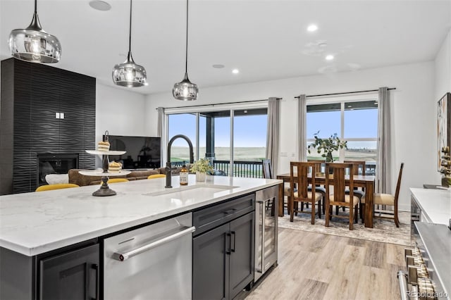 kitchen with light hardwood / wood-style flooring, dishwasher, a wealth of natural light, and a center island with sink