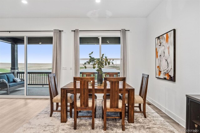 dining area with a water view, hardwood / wood-style flooring, and a healthy amount of sunlight