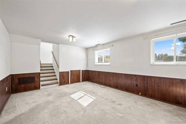 spare room with light colored carpet and wooden walls