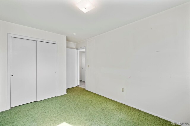 unfurnished bedroom featuring light carpet and a closet