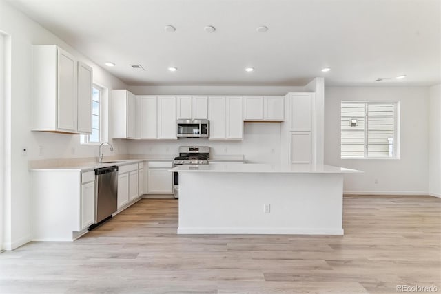 449 S Salida St, Aurora, CO 80017 - kitchen with appliances with stainless steel finishes, a sink, a center island, white cabinetry, and light countertops