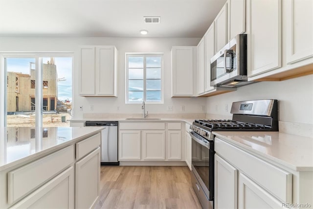 449 S Salida St, Aurora, CO 80017 - kitchen with appliances with stainless steel finishes, a sink, white cabinetry, and light wood finished floors