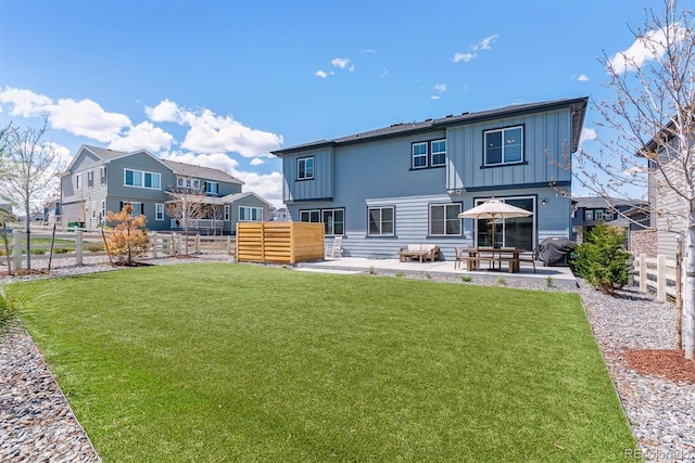 rear view of house with a fenced backyard, board and batten siding, a patio area, and a yard