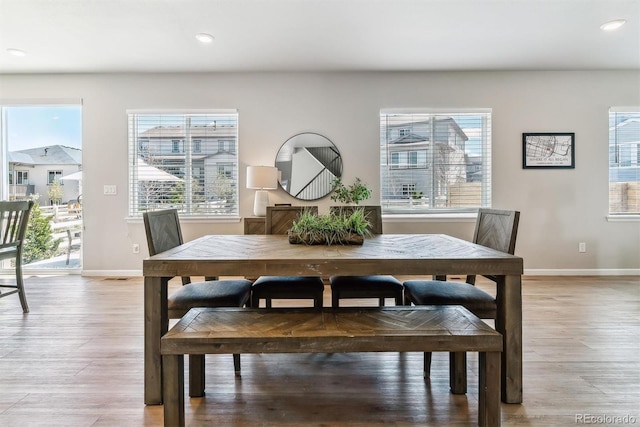 dining room featuring light wood-style floors, baseboards, and a wealth of natural light