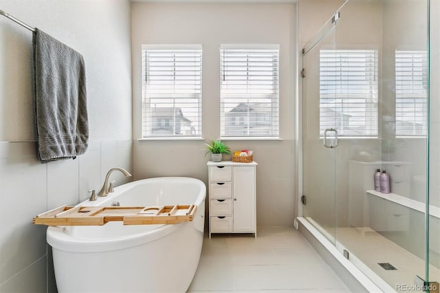 bathroom featuring a freestanding tub, tile patterned floors, and a stall shower