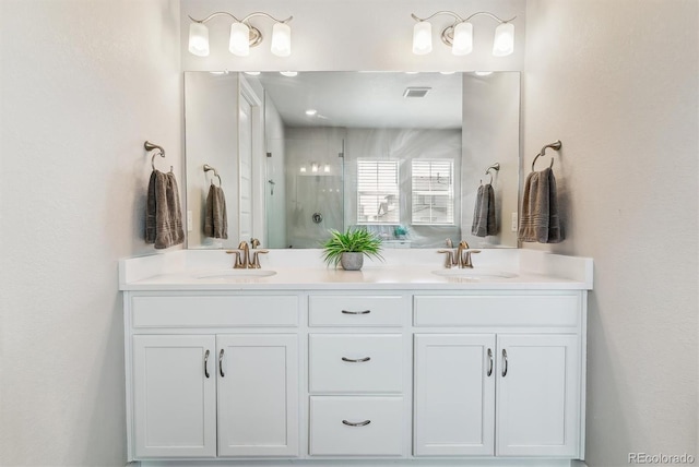 full bath featuring a sink, a shower stall, double vanity, and visible vents