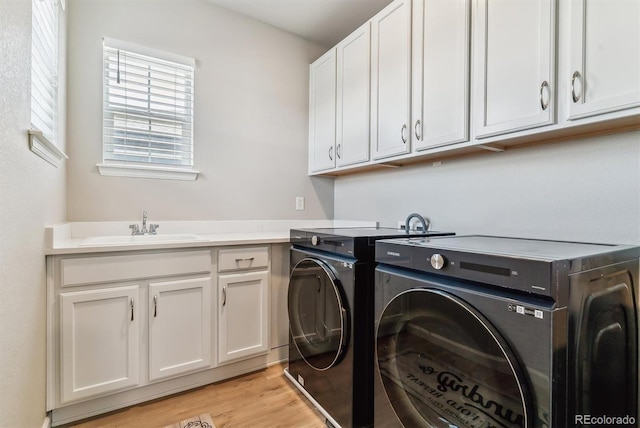 laundry area with a sink, light wood finished floors, cabinet space, and washer and dryer