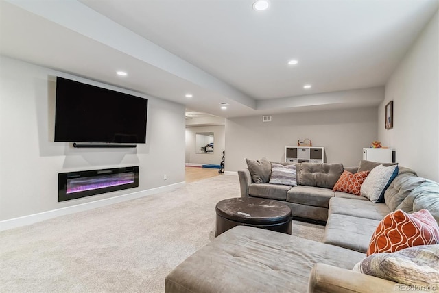 living area featuring recessed lighting, baseboards, light colored carpet, and a glass covered fireplace