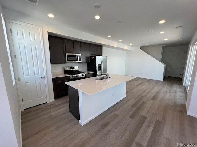 6599 N Netherland St, Aurora, CO 80019 - kitchen with appliances with stainless steel finishes, light wood-style floors, recessed lighting, an island with sink, and light countertops