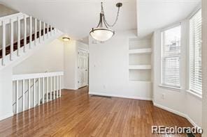 unfurnished dining area featuring a healthy amount of sunlight, built in features, and dark wood-type flooring