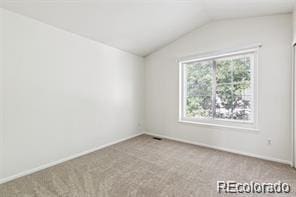 carpeted empty room with vaulted ceiling