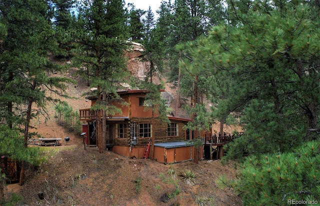 rear view of property featuring a jacuzzi and a deck