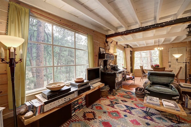 interior space featuring wood walls, plenty of natural light, an inviting chandelier, and beamed ceiling