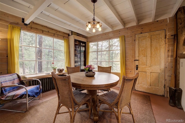 dining room with wooden walls, an inviting chandelier, and beam ceiling