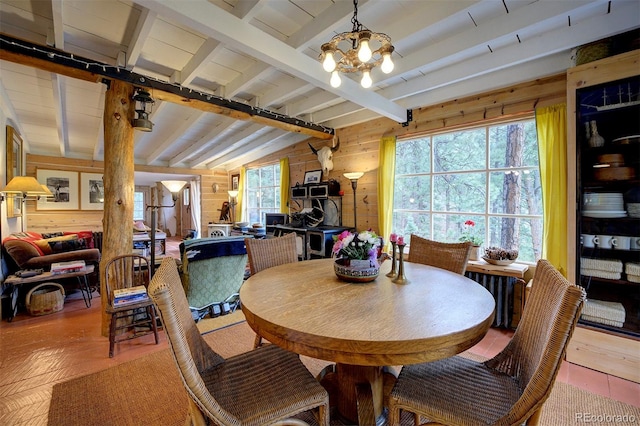 dining area with a notable chandelier, wooden walls, and beamed ceiling