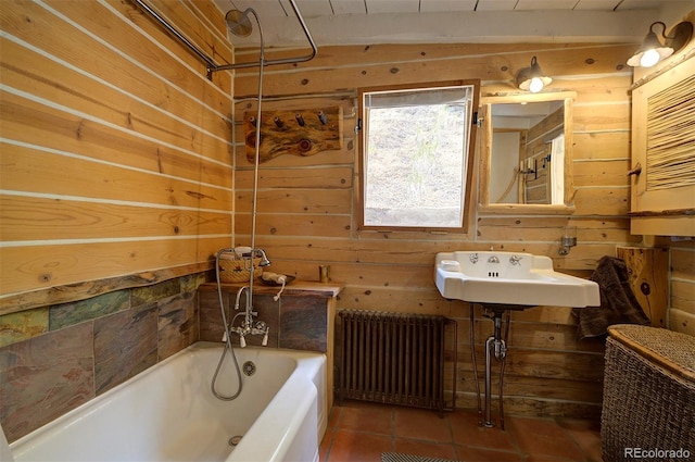 bathroom featuring tile patterned flooring, a bathing tub, sink, wood walls, and radiator