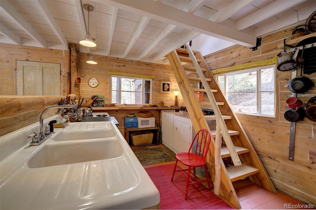 kitchen with wood walls, tile patterned flooring, beamed ceiling, and washing machine and dryer