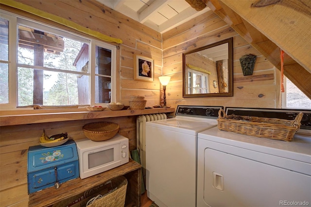 laundry area featuring wooden walls and washing machine and dryer