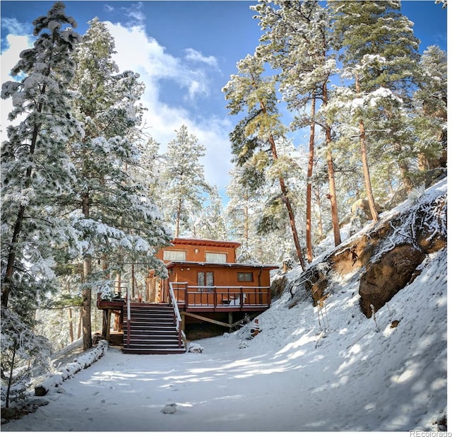 snow covered rear of property with stairs and a deck