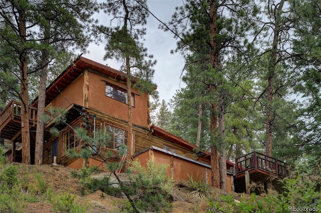 rear view of house with stairway and stucco siding