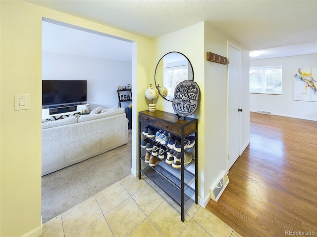 hall featuring light tile patterned floors and baseboards