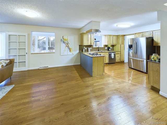 kitchen with stainless steel appliances, a peninsula, light wood-style flooring, baseboards, and a textured ceiling