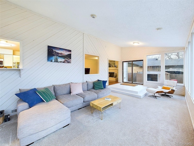 living room featuring carpet flooring, a textured ceiling, and wooden walls