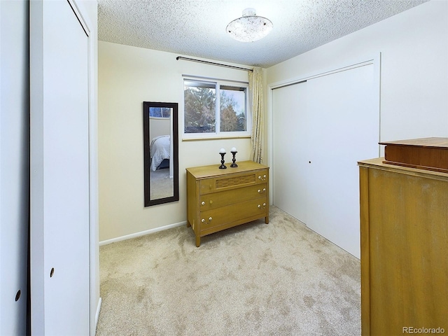 bedroom featuring light colored carpet, a textured ceiling, and a closet