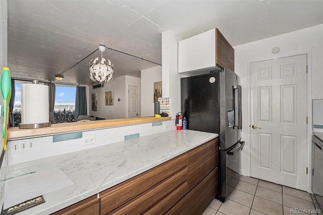 1020 15th St Unit 12C, Denver, CO 80202 - kitchen with fridge with ice dispenser, a chandelier, light tile patterned flooring, brown cabinets, and light stone counters