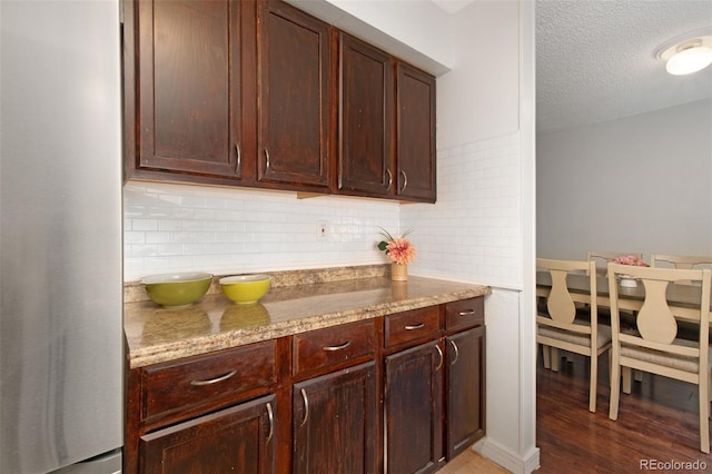 3341 S Monaco Pkwy Unit A, Denver, CO 80222 - kitchen featuring freestanding refrigerator, backsplash, a textured ceiling, light stone counters, and light wood-style floors