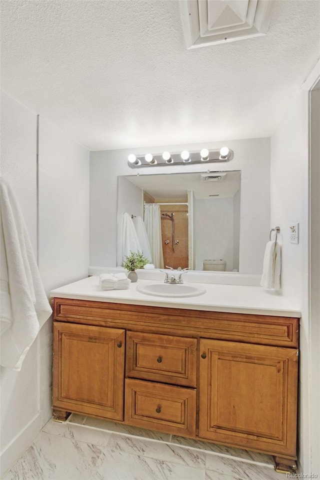 3341 S Monaco Pkwy Unit A, Denver, CO 80222 - bathroom featuring vanity, marble finish flooring, curtained shower, and a textured ceiling
