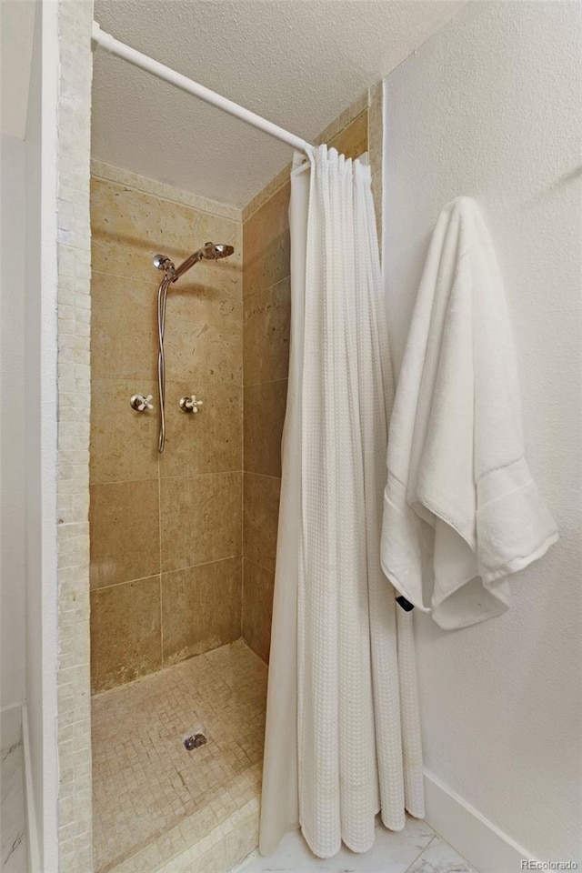 3341 S Monaco Pkwy Unit A, Denver, CO 80222 - bathroom featuring a shower stall, a textured ceiling, and baseboards