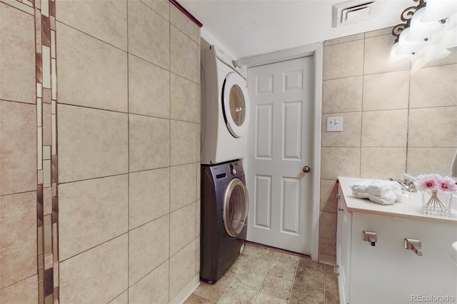3341 S Monaco Pkwy Unit A, Denver, CO 80222 - laundry area with stacked washer / dryer, tile walls, and light tile patterned floors