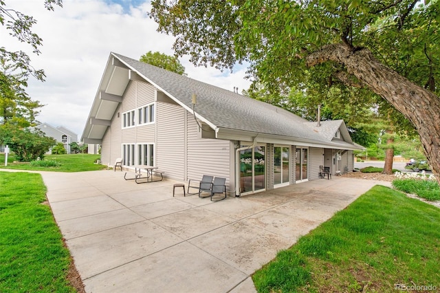 3341 S Monaco Pkwy Unit A, Denver, CO 80222 - view of property exterior featuring a patio, a shingled roof, and a lawn