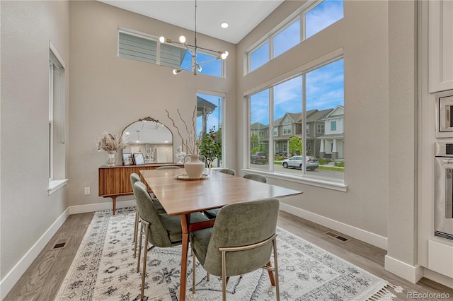 6366 N Emporia St, Denver, CO 80238 - dining space featuring a chandelier, light wood-style flooring, and a high ceiling