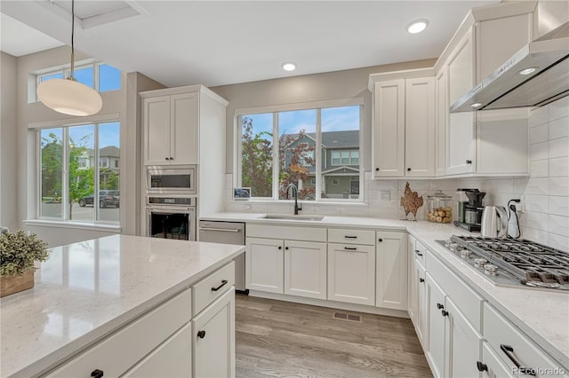 6366 N Emporia St, Denver, CO 80238 - kitchen with wall chimney exhaust hood, stainless steel appliances, plenty of natural light, white cabinetry, and recessed lighting