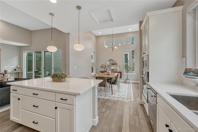 6366 N Emporia St, Denver, CO 80238 - kitchen featuring light wood-style flooring, light stone countertops, stainless steel appliances, pendant lighting, and a high ceiling