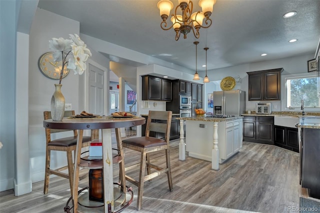 2770 Rossmere St, Colorado Springs, CO 80919 - kitchen featuring stainless steel appliances, light wood finished floors, light stone countertops, a kitchen island, and recessed lighting