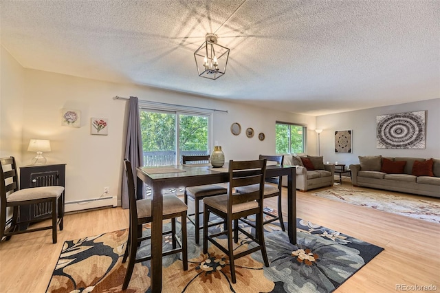 7020 E Girard Ave Unit 206, Denver, CO 80224 - dining area with wood finished floors, a textured ceiling, a baseboard radiator, and a chandelier