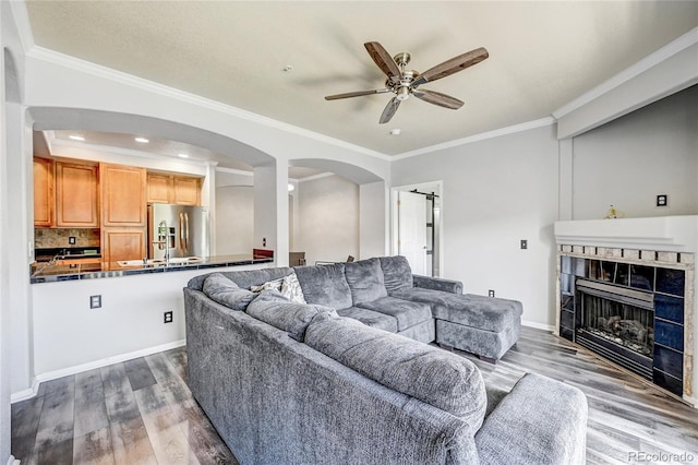 living room featuring hardwood / wood-style flooring, ceiling fan, and ornamental molding