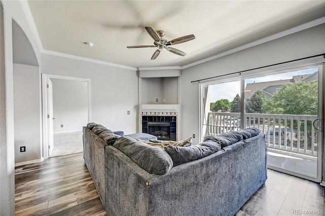 living room with hardwood / wood-style flooring, ceiling fan, ornamental molding, and a tile fireplace