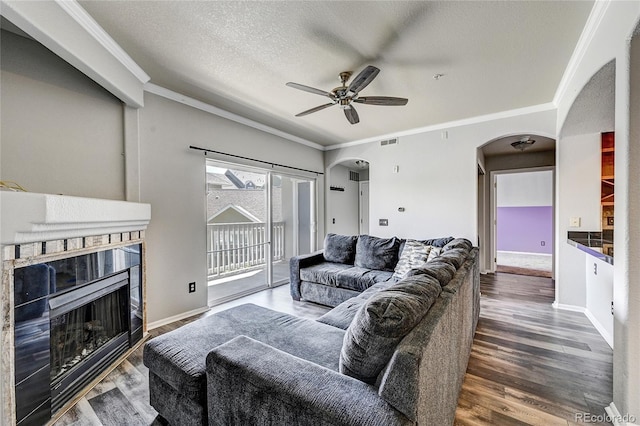 living room featuring a textured ceiling, dark hardwood / wood-style floors, ceiling fan, and crown molding