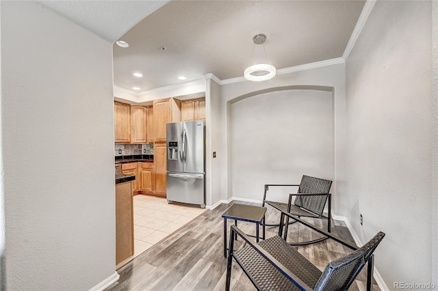 kitchen featuring decorative backsplash, stainless steel refrigerator with ice dispenser, light wood-type flooring, light brown cabinetry, and ornamental molding