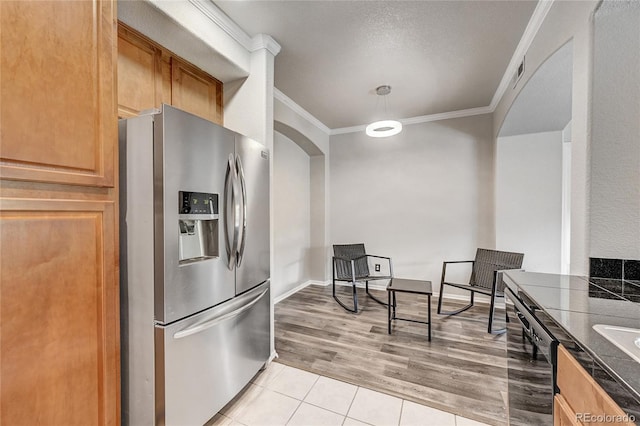 kitchen featuring stainless steel fridge with ice dispenser, ornamental molding, and light tile patterned floors