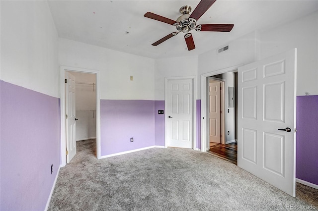 unfurnished bedroom featuring carpet flooring, a closet, a spacious closet, and ceiling fan