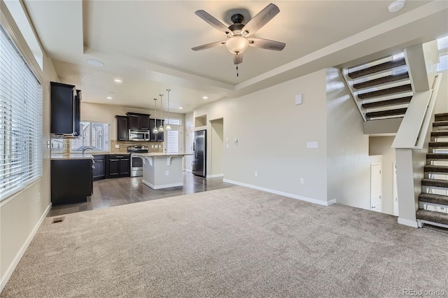 2564 Sweet Wind Ave, Castle Rock, CO 80109 - unfurnished living room featuring dark carpet, ceiling fan, stairway, a raised ceiling, and recessed lighting