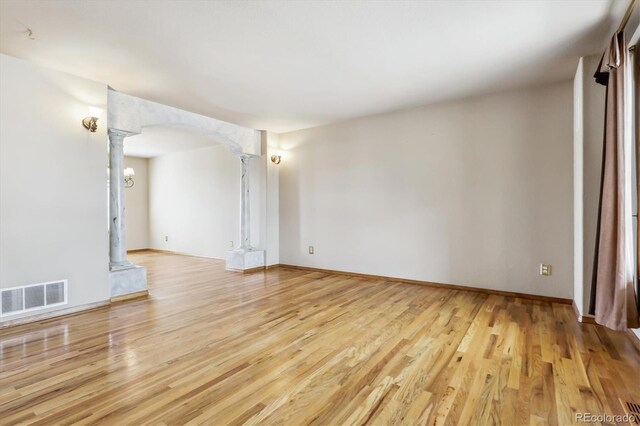 9920 Glenellen Dr, Peyton, CO 80831 - spare room featuring visible vents, decorative columns, arched walkways, and wood finished floors
